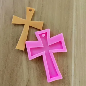 Close-up of cross-shaped pink silicone mold and resin piece with heart cutout detail
