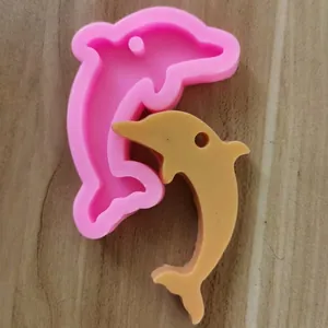 Detailansicht der rosa Delfin Silikonform mit Harzstück auf einer Holzoberfläche