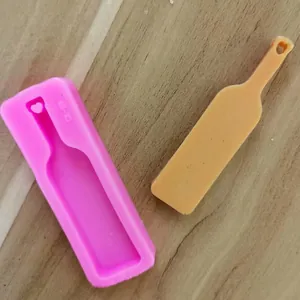 Detail einer rosa Silikonform für Weinflaschen neben einem fertigen gelben Kunstharzguss