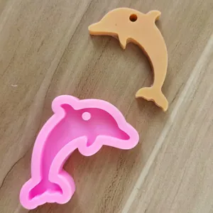 Makroansicht einer rosa Delphin-Silikonform mit Harzguss auf Holz-Hintergrund