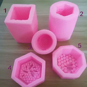 Détail de cinq moules en silicone rose avec motifs d'alvéoles et d'abeilles pour le bricolage