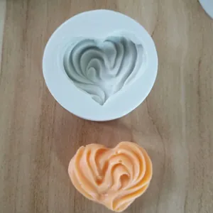 Vista dettagliata di uno stampo in silicone a cuore e del suo prodotto a cuore arancione.