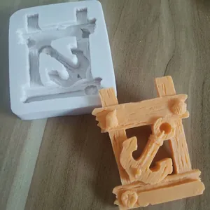 Detailed macro view of nautical anchor silicone mold alongside finished resin craft.