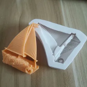 Detail view of a sailboat silicone mold with an orange fondant sailboat model.