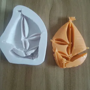 Detailed view of nautical sailboat silicone mold beside an orange fondant replica