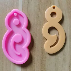 Vergleich einer rosa Silikonform und eines beigen Kunstharzanhängers in künstlerischer Form.