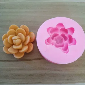 Detail view of a pink flower shaped silicone mold and a finished plaster ornament on wood