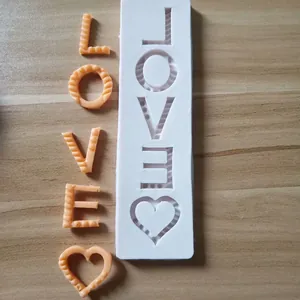 Close-up of LOVE letters and heart silicone mold with finished orange resin samples