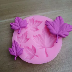 Close-up detail of pink silicone maple leaf mold with purple fondant leaves for baking