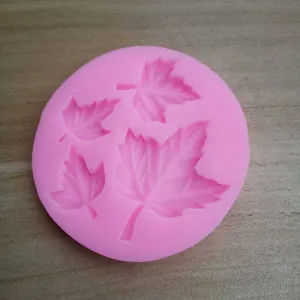 Detailed view of a pink silicone mold with four maple leaf patterns for cake decorating.