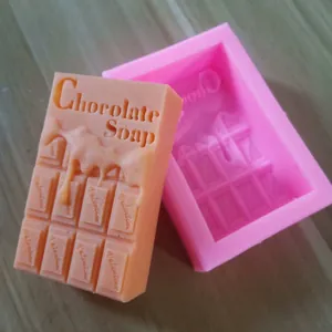 Primo piano di un sapone a forma di cioccolato e del suo stampo in silicone rosa.
