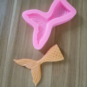Detailansicht der rosa Meerjungfrauenschwanz-Silikonform mit fertigem orangefarbenem Fondant.