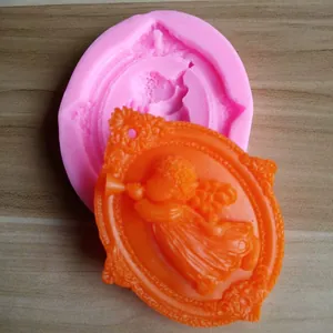 Close-up of pink silicone mold showing finished orange trumpet angel soap relief on wood