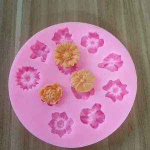 Détail d'un moule en silicone rose à onze cavités avec divers motifs de fleurs