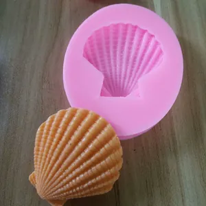Close-up view of a pink seashell silicone mold and an orange shell-shaped resin product.
