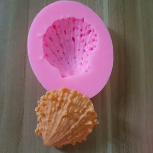 Close-up view of pink silicone seashell mold and finished orange fondant craft details.
