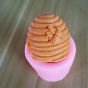 Close-up of pink 3D beehive silicone mold with finished orange beehive wax candle