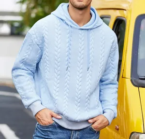 Vue détaillée montrant le motif jacquard en maille torsadée d'un sweat bleu clair homme.