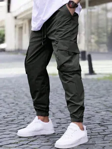Detail of dark olive green men's cargo joggers with drawstring waist and side pockets.