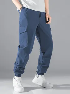 Detail view of blue men's cargo jogger pants with side flap pockets and elastic cuffs.