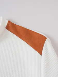Detailansicht von weißem Waffelstrickstoff und orangefarbenem Schultereinsatz am Hemd