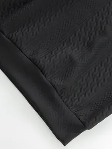 Macro view showing the intricate jacquard texture and ribbed cuff of black sweatshirt