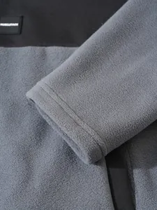 Gros plan sur la texture du tissu polaire gris doux et le détail du poignet