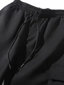 Professional detail shot of black cargo joggers with elastic waistband and drawstring.