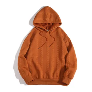 Gros plan détaillé du sweat à capuche orange montrant la texture en maille torsadée