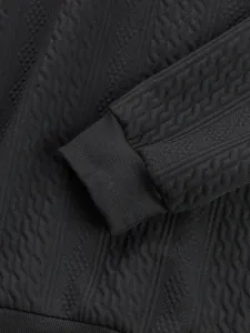 Close-up detail of black men's sweatshirt showing textured jacquard fabric and ribbed cuff