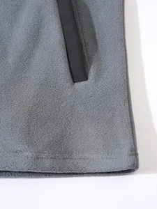 Détail rapproché du tissu polaire gris et du bord de la poche d'une veste d'hiver.