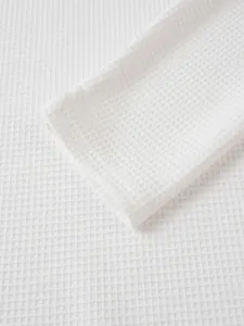 Makro-Detail der weißen Waffelstrick-Struktur und Manschette eines Herren-Henley-Shirts