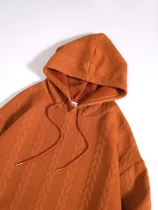 Vue rapprochée détaillée du tissu texturé à motif de torsades d'un sweat à capuche orange