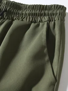Close-up detail of olive green men's cargo pants showing elastic waist and pocket stitching