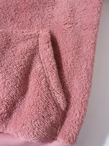 Nahaufnahme der rosa flauschigen Fleece-Stoffstruktur und Tasche am Hoodie