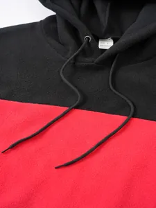 Close-up detail of black and red color-block mens fleece hoodie showing soft warm fabric texture
