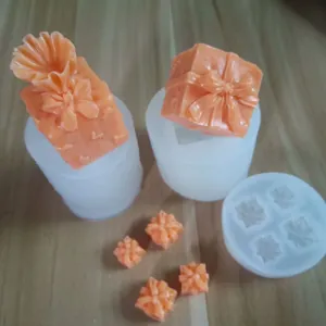 Detailed view of 3D gift box silicone molds and finished orange decorative resin casts on wood