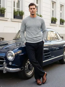 Elegant male model in grey textured crewneck sweater leaning on classic vintage car