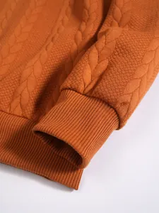 Gros plan sur le tissu en maille jacquard texturé et le poignet côtelé d'un sweat à capuche orange