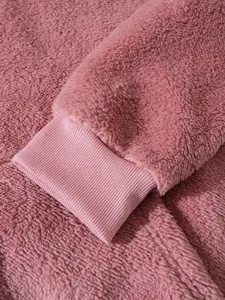 Makrodetail von weichem rosa Sherpa-Fleece und Rippbündchen an einem lässigen Herrenhoodie