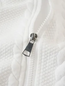 Close-up view of silver metal zipper pull on white jacquard hoodie fabric texture