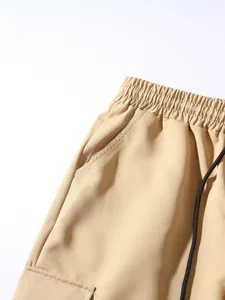 Close-up of beige cargo joggers with elastic drawstring waistband and textured cotton fabric.