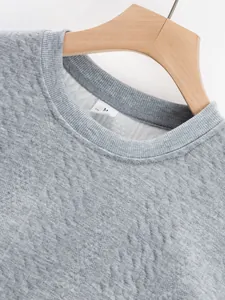 Close-up of grey jacquard sweatshirt neckline showing ribbed collar and size M label