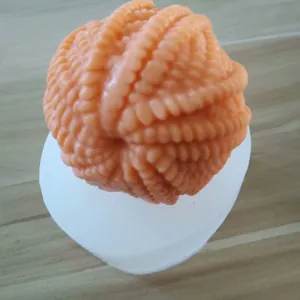 Detailed close-up of 3D yarn ball silicone mold with finished orange candle sample