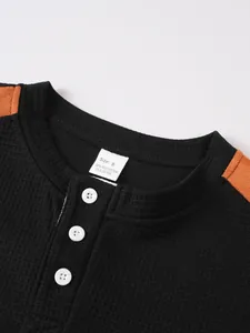 Detailansicht eines schwarzen Henley-Shirts aus Waffelstrick mit orangen Schulterdetails