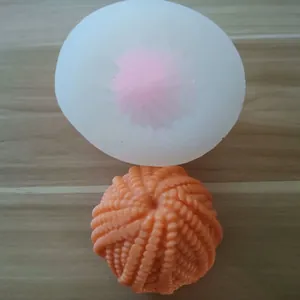 Close-up of 3D yarn ball silicone mold with finished orange textured candle sample