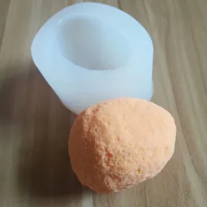 Detail of 3D stone-shaped silicone mold with textured orange gypsum cast on wood