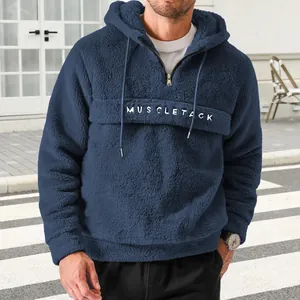 Detail showing texture of navy blue fuzzy fleece hoodie with half-zip and letter print