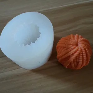 Close-up detail showing the white silicone mold and an orange 3D textured wool ball candle.