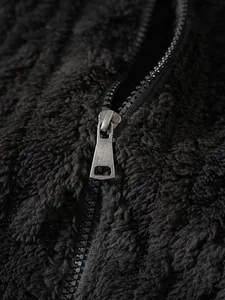 Detailopname van een zwart pluizig jack met zachte textuur en ritsdetail